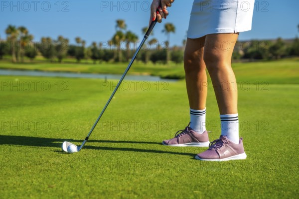Female golfer concentrating intensely while hitting the golf ball on a bright, sunny day at the