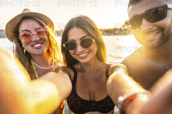 Cheerful young friends enjoying their summer vacation at the beach, capturing joyful moments