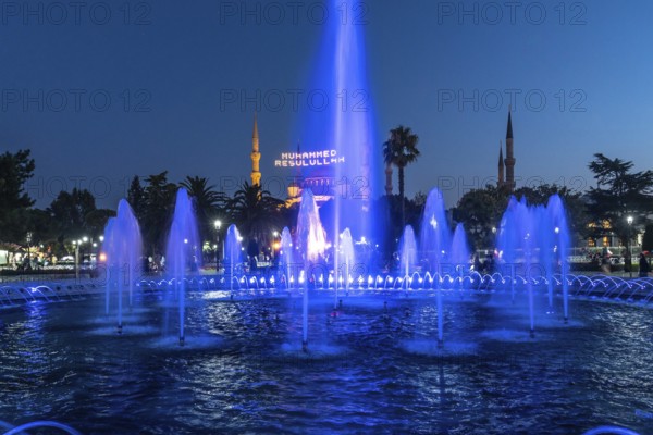 Majestic mosque providing a backdrop to illuminated fountains, creating a captivating scene in