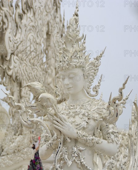 White sculpture holding lotus flowers at the famous wat rong khun, also known as the white temple,