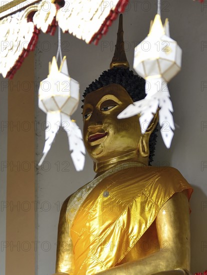 Majestic golden buddha statue wearing a yellow robe, serene and peaceful, inside a traditional thai