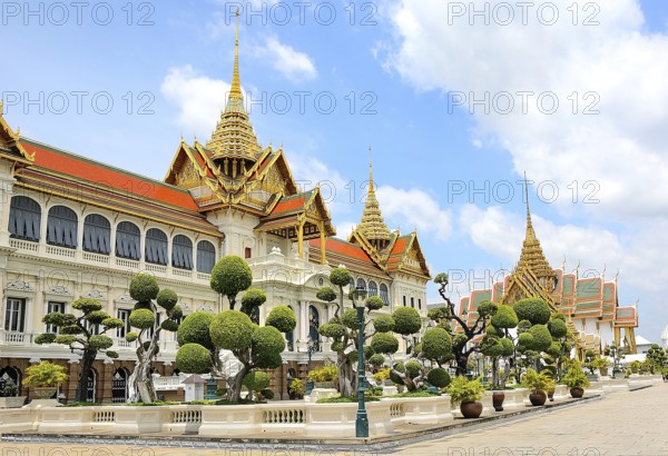 Ornate buildings with golden roofs and decorative elements stand amidst manicured gardens,