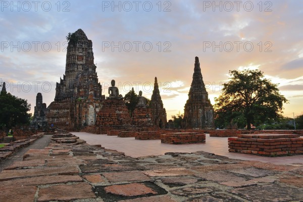 Serene buddha statues sit amidst crumbling temple ruins, bathed in the golden light of a beautiful