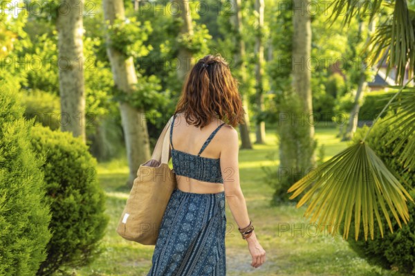 Tourist walking through a picturesque park in salies de bearn, france, carrying a tote bag and