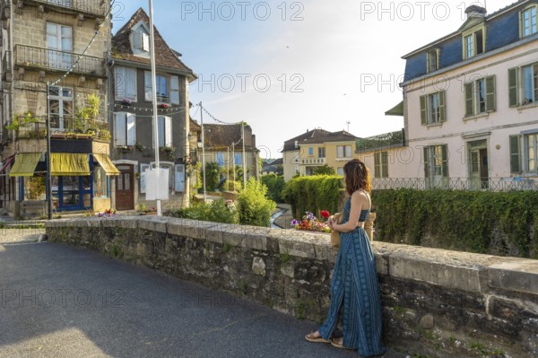 Tourist holding flowers and enjoying the view of a canal in the charming village of salies de