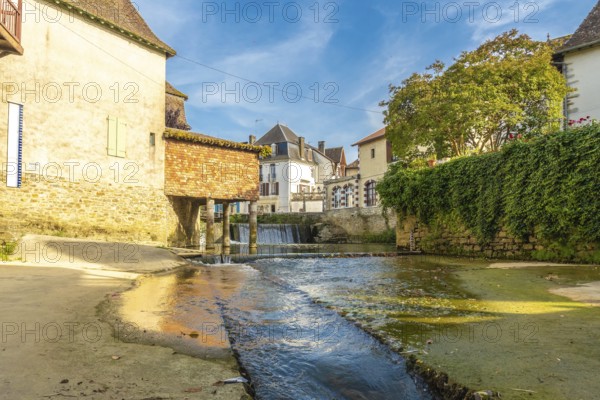 Scenic view of a small waterfall flowing through the charming village of salies de bearn in the