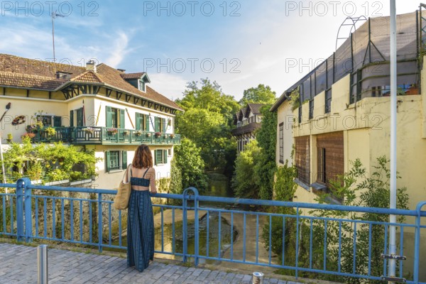 Tourist admiring the picturesque canal and traditional houses in the charming village of salies de