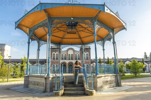Tourist ascending stairs of a gazebo in a park in salies de bearn, france, enjoying a summer