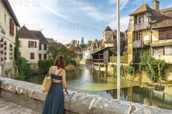 Young woman admiring the saleys river flowing through the picturesque village of salies de bearn, a