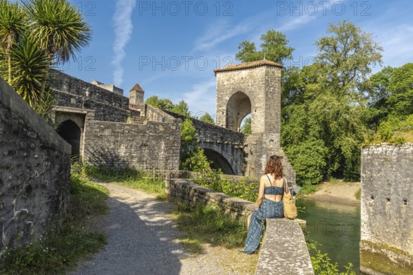 Young woman enjoying the scenic view of the historic bridge and fortifications in sauveterre de