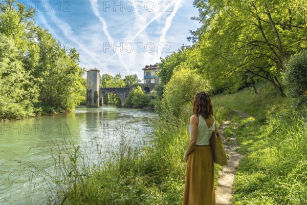 Woman enjoying summer vacations in french countryside admiring the medieval bridge and tower of