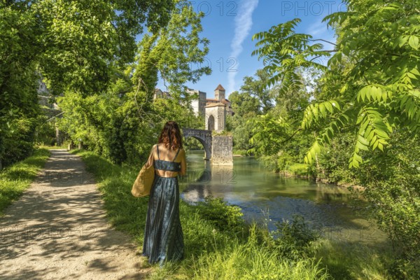 Tourist admiring the medieval bridge and the church of saint andre in sauveterre de bearn, a