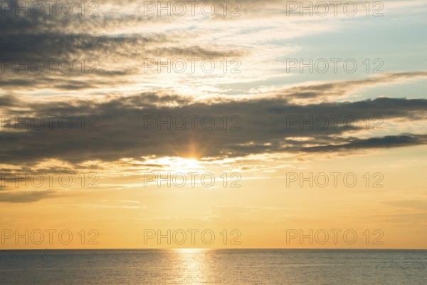 Picturesque sunset over the sea with soft clouds and golden light, sun star, clouds, reflecting