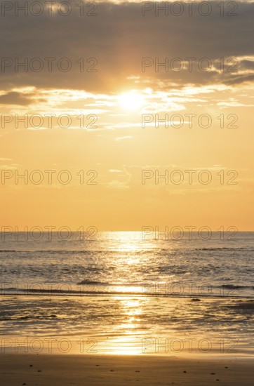 Picturesque sunset over the sea with grey clouds and golden light, sun star, clouds, reflecting