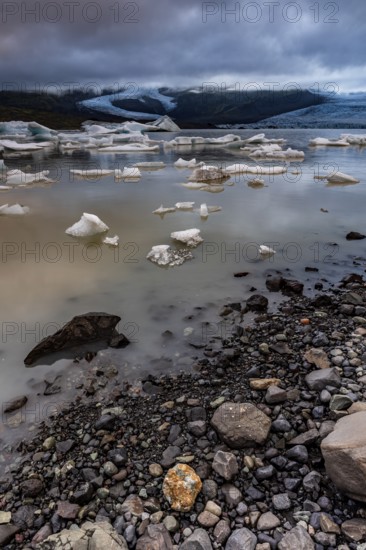 Ice floes, lake, shore, stones, glacier tongue behind, glacier, glacier lagoon, cloudy, summer,
