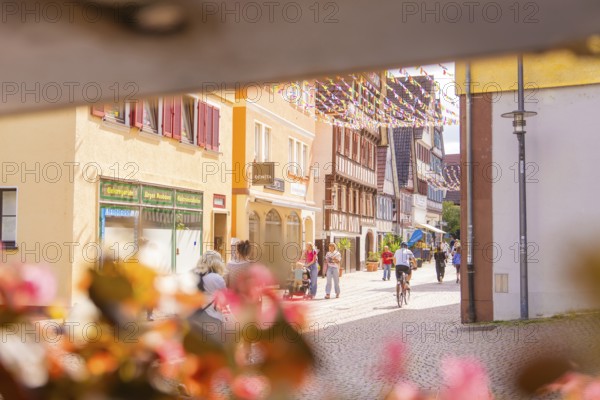 Lively street in a charming old town with cyclists and passers-by, surrounded by historic houses,