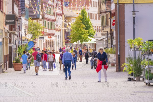 Lively pedestrian zone with people in a town with traditional half-timbered buildings and shops,