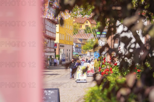 Old town street with full shops and colourful decoration, lively with passers-by, small town pearl