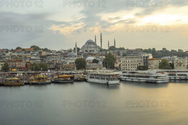 Ferryboats navigating the golden horn at sunset, with the majestic suleymaniye mosque dominating