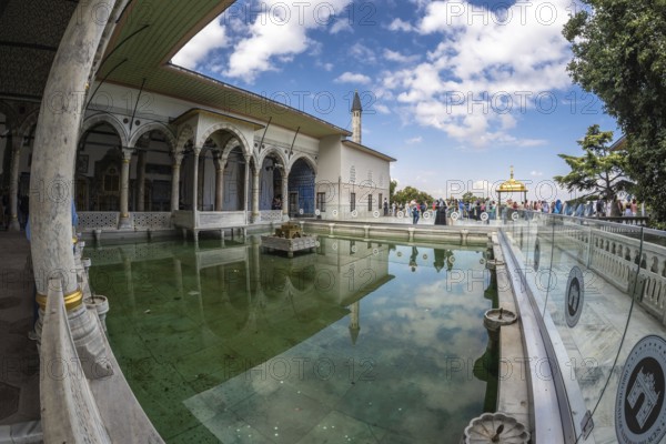Tourists walking around the courtyard with reflecting pool of the topkapi palace in istanbul,