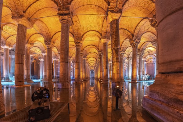 Warm orange light illuminating majestic columns and arches reflecting on the water surface of the