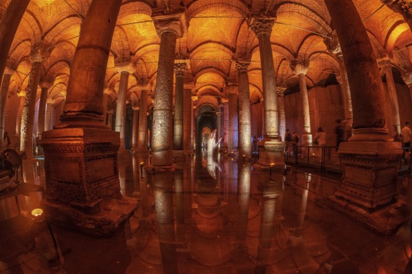 Tourists walking on a walkway in the basilica cistern in istanbul, turkey, with warm light