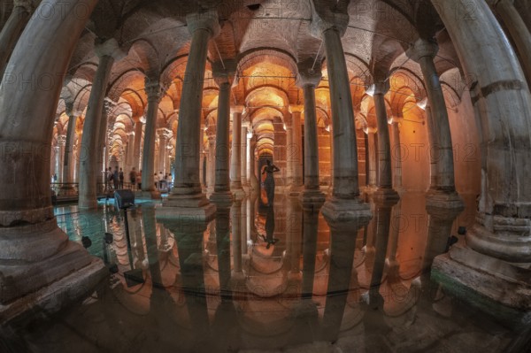 Ancient underground basilica cistern reflecting on water surface with tourists and medusa head