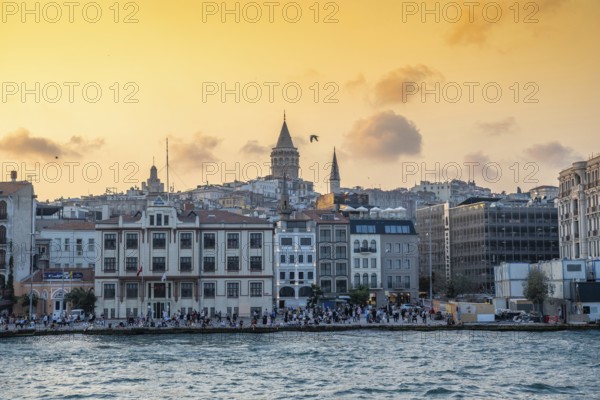 Tourists enjoying sunset view of galata tower and cityscape of istanbul, turkey, from the bosphorus