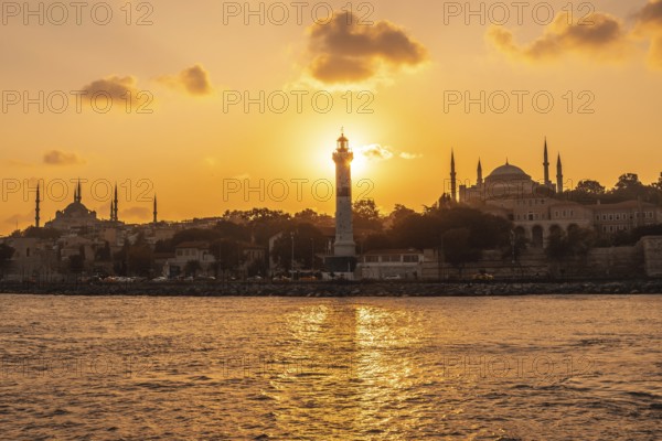Scenic sunset over istanbul with prominent lighthouse, mosque and hagia sophia silhouettes,