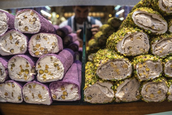 Colorful turkish delight lokum rolls, coated in pistachios and filled with walnuts, stacked on