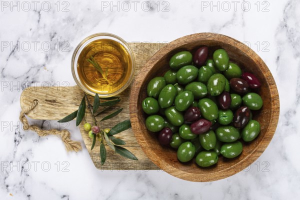 Chalkidiki olives, classic Greek green olives, in a bowl on a cutting board, top view, without