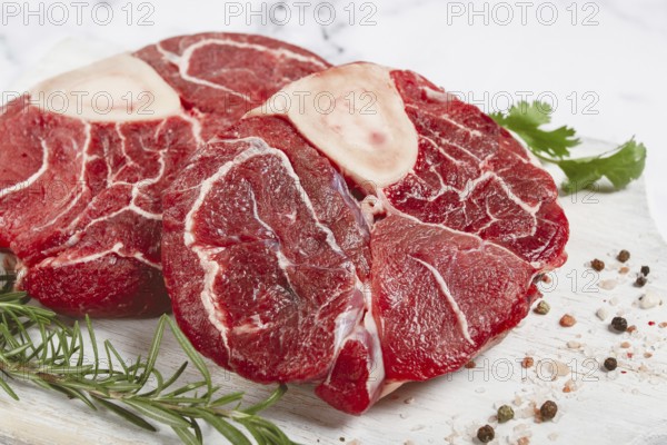 Knuckle on the bone, raw meat for ossobuco, on a wooden chopping board, with a sprig of rosemary,