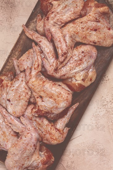 Chicken wings, marinated and laid out on a wooden platter, ready for cooking, grilling or baking,
