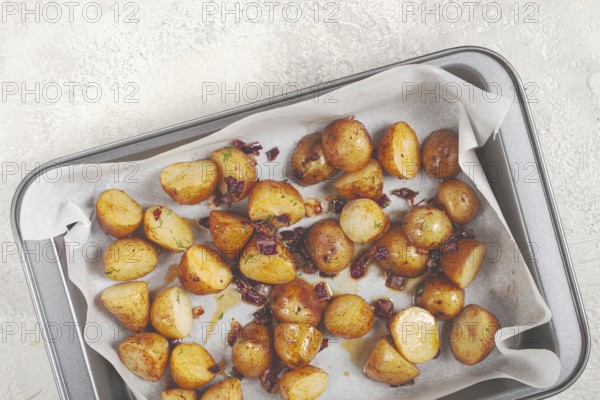 Golden-brown roasted potatoes are arranged on a baking tray lined with parchment paper. They are