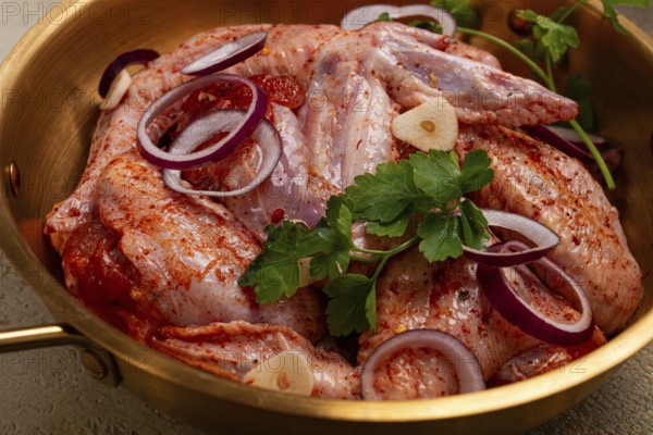 Chicken wings, in a brass saucepan, ready for cooking, grilling or baking, in a home kitchen, no