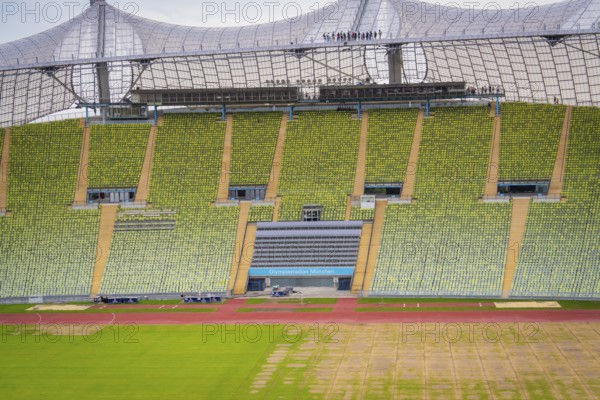 Detailed view of a stadium section with green rows of seats and striking roof background,
