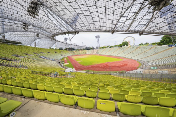 Overview of the stadium with green seats and red running track, framed by an impressive roof