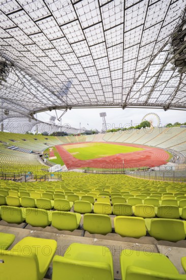 Panoramic view of stadium with yellow-green seats and red running track under a filigree roof,