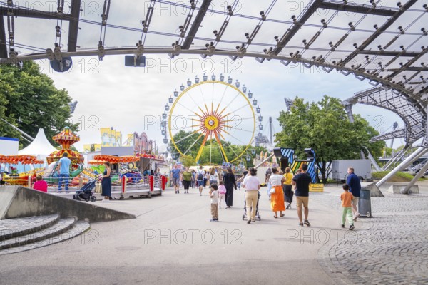 Lively amusement park with Ferris wheel and lots of people strolling around, Olympic Park, Munich,