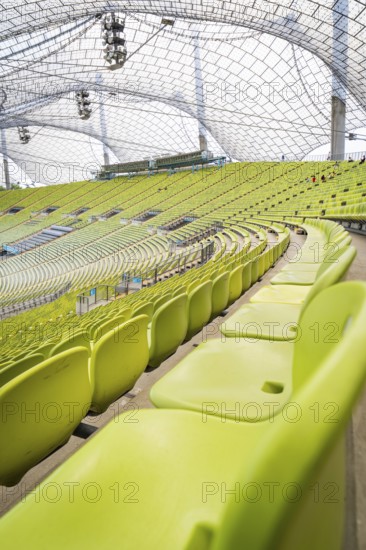 Close-up of empty green seats with a view of a modern glass roof, Olympiapark, Munich, Germany