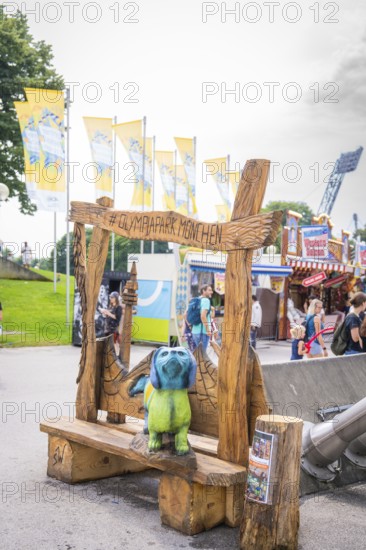 Wooden bench with colourful bear figure and lettering in amusement park with background of