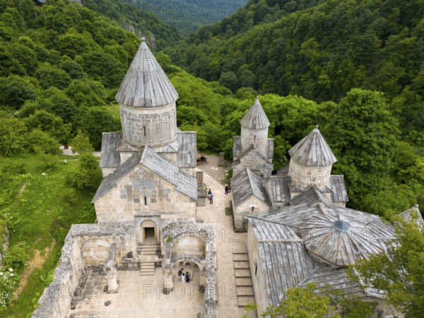 Historic stone monastery building, embedded in a wooded hilly landscape, aerial view, Haghartsin