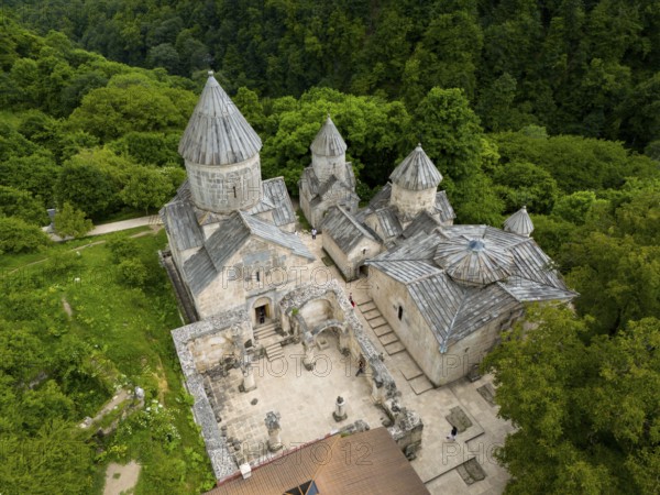 Aerial view of a historic monastery with striking stone architecture, surrounded by forest, aerial