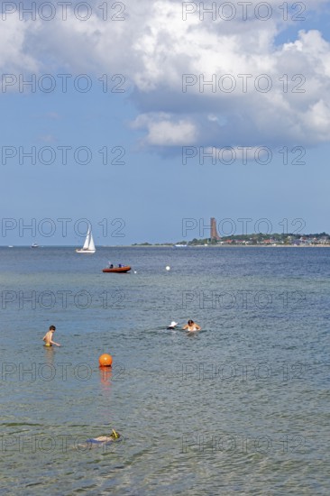 Sailing boat, rubber dinghy, people bathing, in the background the naval memorial in Laboe, Kiel