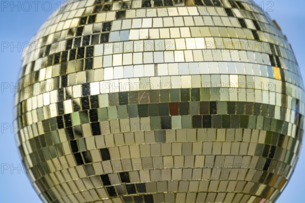 Golden disco ball, small mirrors, distributed like a mosaic, reflect light and create lighting