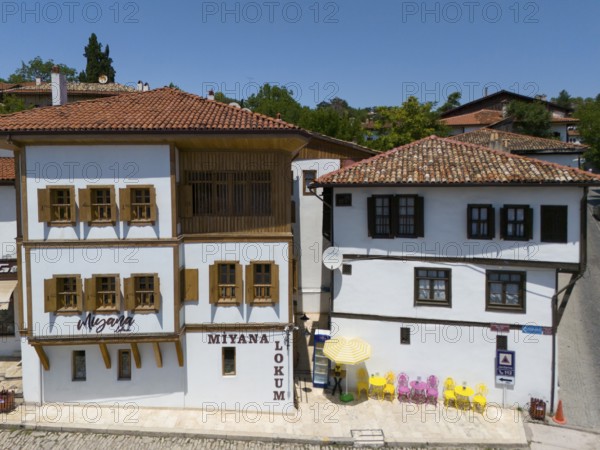 Two historic buildings with wooden windows and red roofs in sunny weather in a quiet street scene,