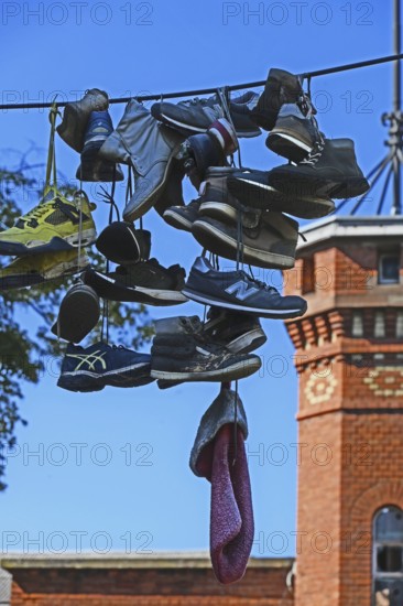 Shoes hanging on a leash in the courtyard of a residential home for addicts, each shoe a reminder