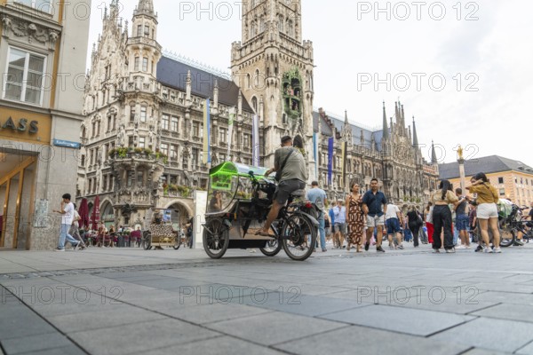 Lively town hall square with tourists in front of impressive Gothic architecture, Marienplatz,