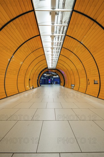 Long, illuminated underground railway tunnel in bright orange, leading into the distance,