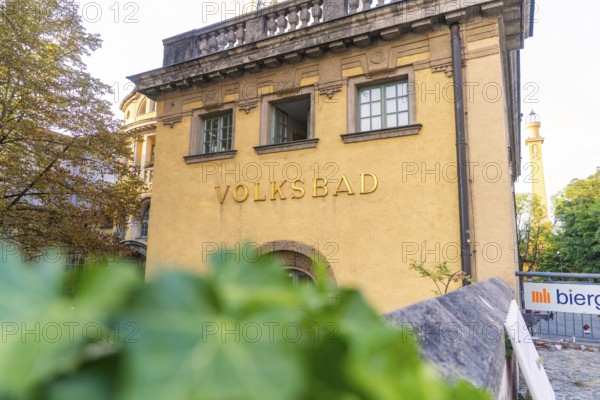 Historic public swimming pool with yellow façade, traditional architecture and surrounded by trees,